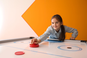 Little girl playing air hockey indoors