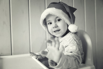 A small child in a santa hat monochrome