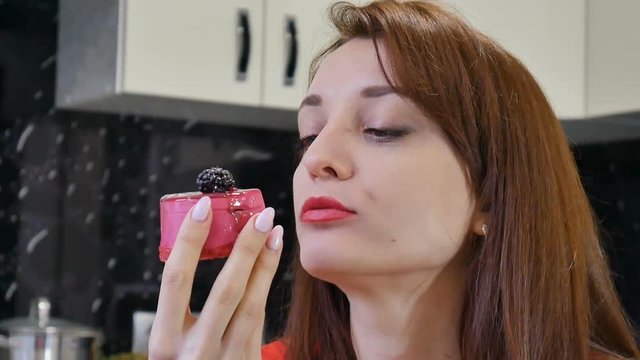 Happy woman eating a piece of cake sitting at the kitchen at her home