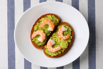 sandwich with avocado guacomole and srimp on plate