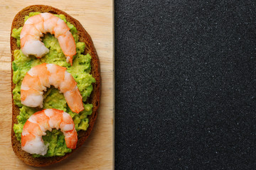 shrimp and guacamole with bread on dark background