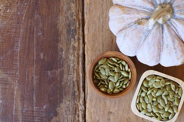 Pumpkin grain in wooden bowl and fresh pumpkin fruit on classic wooden table background, cereal