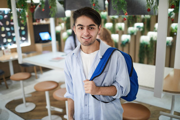 Successful college student with backpack on shoulder visiting cafe at break between classes