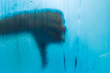 A hand showing dislike outside the foggy window