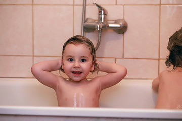 Young children take a bath. Children wash in the bathroom. Brother and sister play in the bathroom during water procedures.