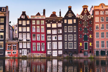 Front view of beautiful colorful traditional Amsterdam houses on the Amstel river bank reflecting...