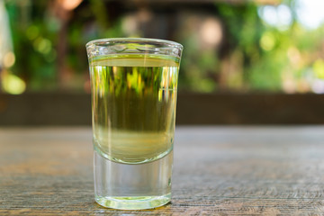Close up of plum brandy or schnapps in a transparent glass on a table in a garden on a sunny day