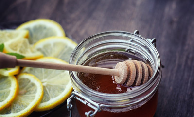 Tea with lemon and mint in nature. A cup of hot mint tea with lemon and honey in a jar. Lemon slices and a spoon with honey to hot tea.