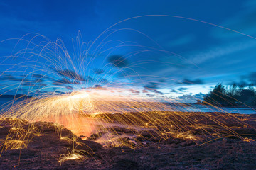Amazing Bokeh fire dancing steel wool sea in the twilight