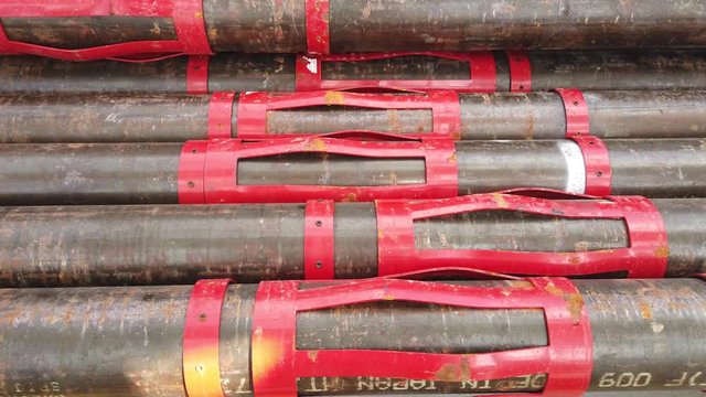 Oil well casing bundles with centralizers installed stacked on the deck of a drilling rig