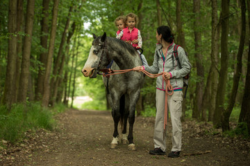 Girl having fun with mother and horse in the woods, young pretty girl with blond curly hair, freedom, joy, movement, outdoor, spring, healthy, happy family, cheerfull, kid on vacation
