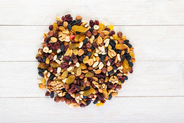 dried fruits and nuts on a wooden white background with a wooden spoon