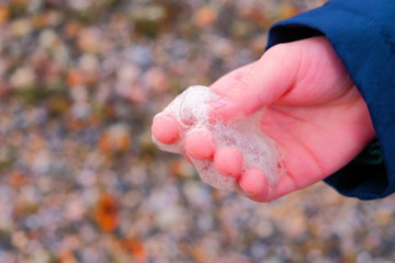 Sea foam in boy's hand. Winter on the seaside.