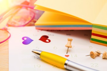 calendar, notebook and pen in the office with pins. reminder of valentines day