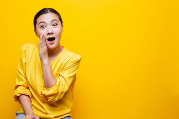 Woman make gossip gesture isolated over yellow background