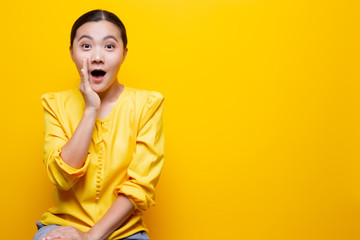 Woman make gossip gesture isolated over yellow background