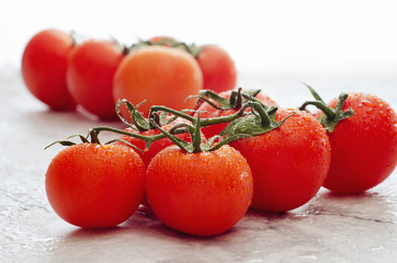 Fresh ripe red cherry tomatoes covered with water drops on a marble background