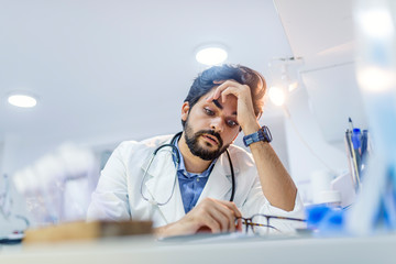 Stressed male doctor sat at his desk