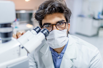 Laboratory. Male Scientist Working At Workplace. Portrait Of Handsome Smiling Happy Man In White Coat Researching With Microscope In Light Modern Laboratory. High Quality Image.