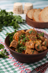Beef goulash is located in a brown bowl on the table