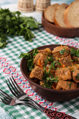 Beef goulash is located in a brown bowl on the table