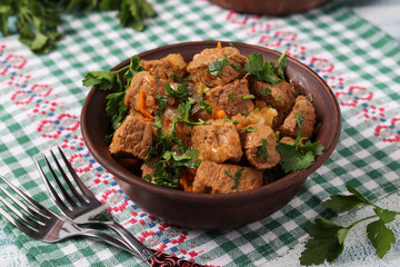 Beef goulash is located in a brown bowl on the table