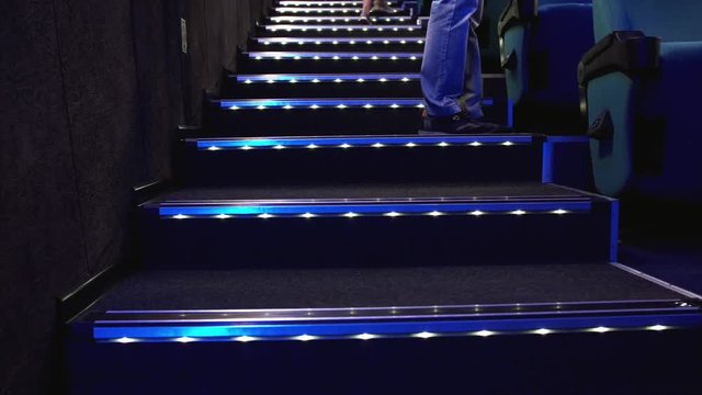 Staircase and people's feet walking up the steps with neon lightning in cinema