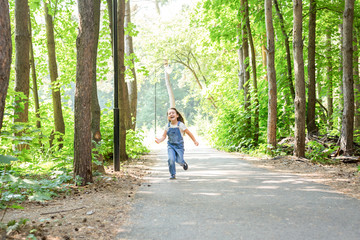 Fototapeta premium Children, childhood and nature concept - Portrait of beautiful small child girl running through the park