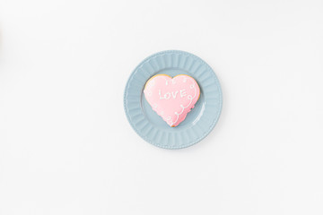 Heart shape cookie with love sign on white textured background