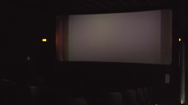 cinema hall with viewers, big screen. Camera is sliding sideways