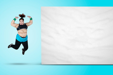 Fototapeta na wymiar Happy fat woman jumps near an empty banner