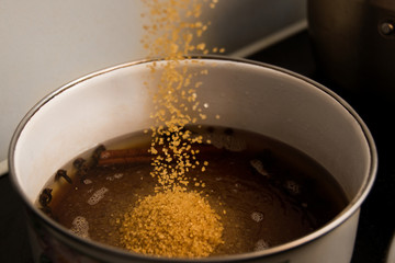 Cane sugar being added into a cooking syrup.