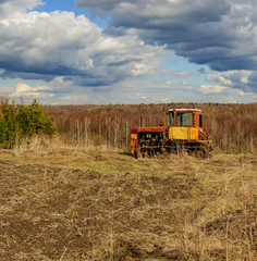 Cloudy day in early spring. Abandoned broken-down tractor. Russia. Leningrad region.