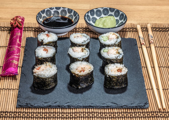 Sushi is a dish made from steamed white rice, rolled in gim with salmon and other ingredients with caviar and served in bite-size slices. Wasabi sauce in saucer.
