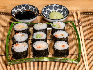 Sushi is a dish made from steamed white rice, rolled in gim with salmon and other ingredients with caviar and served in bite-size slices. Wasabi sauce in saucer.