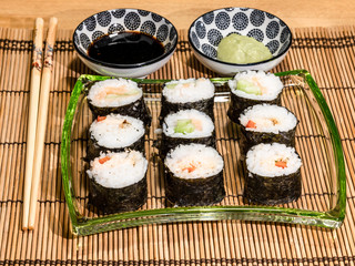 Sushi is a dish made from steamed white rice, rolled in gim with salmon and other ingredients with caviar and served in bite-size slices. Wasabi sauce in saucer.
