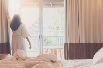 Asian women are staying in a hotel room after wake up on morning. Open the curtain in the room...