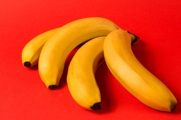 Minimalism style. Fruit pattern with yellow ripe banana fruit over red background.
