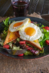 Fried eggs with toast, melted cheese and salad leaves