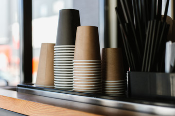 Disposable cups and tubes for cocktails are on the shelf in the coffee shop.