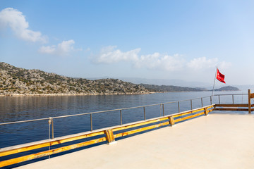 Turkish flag on the background of the Mediterranean Sea. View from the boat.