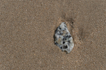 Stone on the beach with copy space on the sand for background.