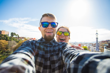 Travel couple happy making selfie portrait with smartphone in Park Guell, Barcelona, Spain.
