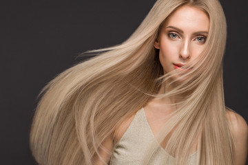 Naklejka premium Beautiful blond girl in move with a perfectly smooth hair, and classic make-up. Beauty face.