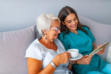 Grandmother sitting on a couch in a sunny room, looking at a photo album and sharing fond memories...