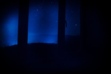 Night scene of stars seen through the window from dark room. Night sky inside dark room.