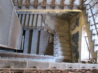 Concrete staircase with wrought iron railings inside an old abandoned house