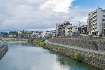Obraz premium Urban or park background featuring Saigawa river and bridges across in residential district of Kanazawa, Japan, in cloudy autumn day in November. 