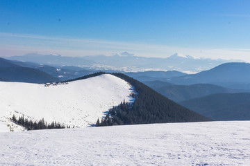 Snow-capped mountains and hills. Mountains Carpathians in Ukraine. Winter mountain landscape. Mountain Bukovel. Panorama from the top of the mountain. Freeride ski slope. Skiing and snowboarding.