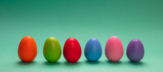 Easter eggs, pastel colors painted, standing in a row, green background